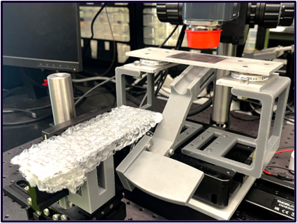 OCT fingertip rig: a 3D-printed cradle holding a tactile sample under an optical coherence tomography microscope.