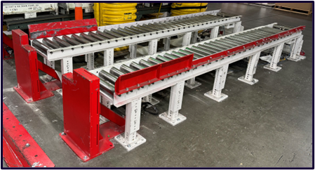 Steel-and-red roller conveyor built to transfer pallets between forklifts and AGVs, photographed in the build bay.
