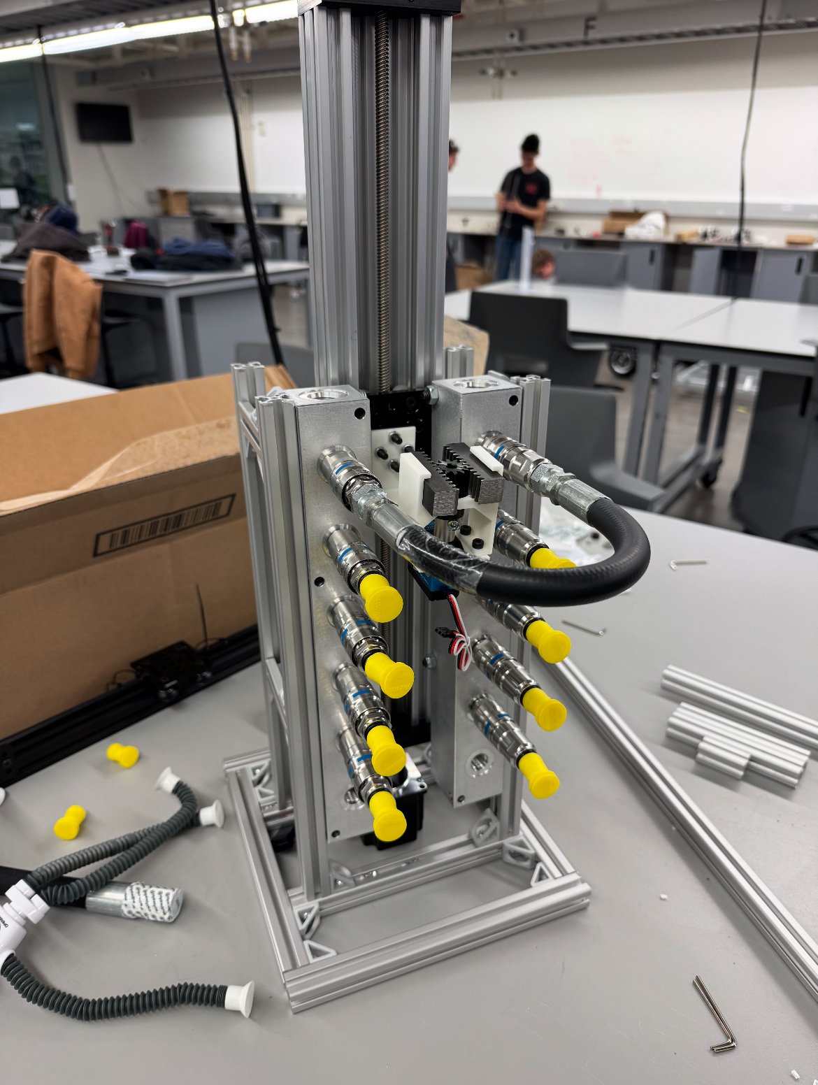 Real photo: the assembled prototype on a lab bench, with hoses, QDs, and the elevator column visible.